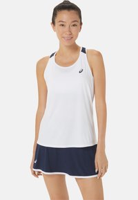 Witte sportieve tanktop met marineblauwe accenten, met een racerback ontwerp en een marineblauwe rok met een witte rand aan de zoom.