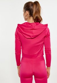 Slimmad, kort hoodie i klar rosa tyg, med huva och långa ärmar, med en jämn textur och utan synliga mönster eller detaljer.