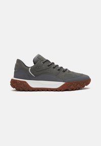Zapatillas bajas grises con una mezcla de materiales lisos y texturizados, suela de goma con picos, entresuela blanca y detalle de logo en el lateral.