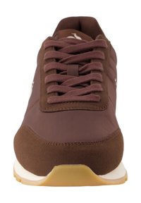 Zapatilla deportiva marrón con una parte superior sintética suave, acentos de ante texturizado, puntera redonda y cierre con cordones. Presenta una suela beige.