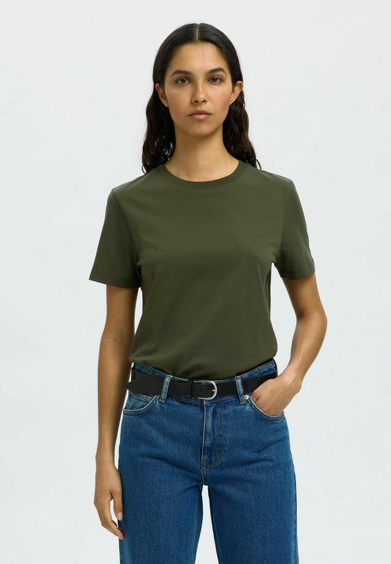 Olijfgroene katoenen T-shirt met korte mouwen, ronde hals en een relaxte pasvorm, gecombineerd met hoogwaardig blauwe denim jeans en een zwarte riem.