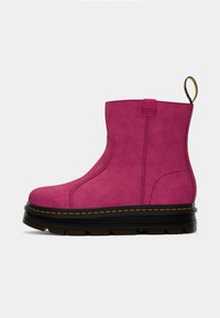 Bottine rose avec une surface texturée, des panneaux latéraux élastiques, une languette, une épaisse semelle noire à plateforme et des détails de couture jaunes.