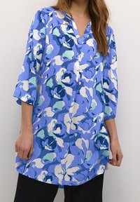 Blaue Blumen-Tunika mit V-Ausschnitt, 3/4-Ärmeln und lockerer Passform. Bietet verschiedene Blau-, Grün- und Beigetöne in einem weichen, leichten Stoff.