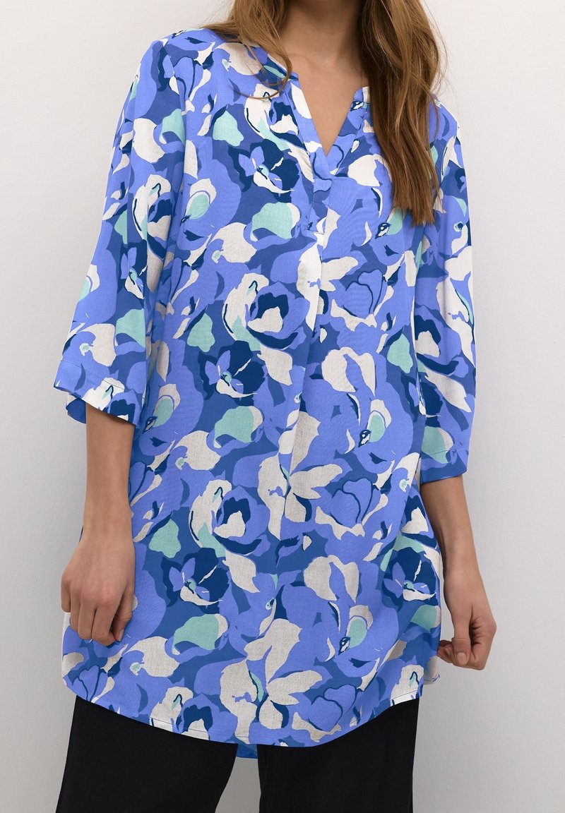 Blaue Blumen-Tunika mit V-Ausschnitt, 3/4-Ärmeln und lockerer Passform. Bietet verschiedene Blau-, Grün- und Beigetöne in einem weichen, leichten Stoff.