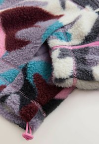 Prim-plan cu material fleece cu model multicolor în nuanțe de violet, albastru, alb și roz, prevăzut cu șnur cu opritor de plastic roz.