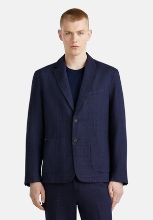 Marine karierter Blazer aus strukturiertem Stoff, mit zwei Fronttaschen und zwei Knöpfen. Figurbetonter Schnitt mit Reverskragen.