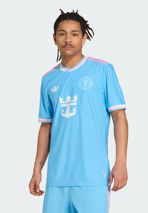 Sky blue athletic jersey with vertical stripes, white logo and crown design, pink accents on the collar and sleeves, lightweight material.