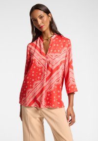 Rote Bluse mit Muster aus leichtem Stoff, featuring einen Mandarin-Kragen, drei Viertel-Ärmel und ein Paisleymuster mit floralen Akzenten.