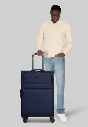 Valigia in tessuto blu navy con due cerniere frontali, manico telescopico e quattro ruote girevoli. Superficie texturizzata con etichetta con marchio.