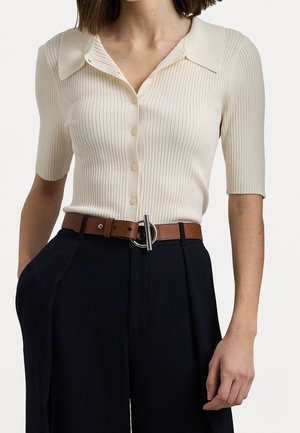 Top en tricot côtelé crème avec un col et des manches courtes, associé à un pantalon noir taille haute et une ceinture en cuir marron.