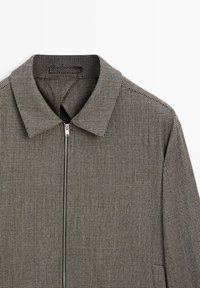Kurtka zapinana na zamek w czarno-białą kratę, z kołnierzem, gładką fakturą materiału i minimalistycznym designem.