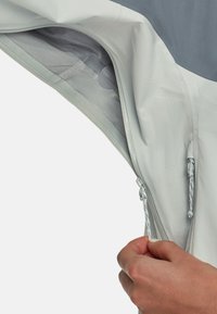 Lys grå lynlåsjakke indvendig med netfor, der har en trækstrop og snøre detaljer. Glat, letvægtsstof.