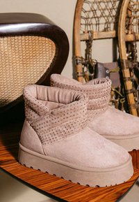 Stivali in camoscio rosa con bordo risvoltato, decorati con borchie ornamentali. Suola spessa in gomma e tessuto strutturato per garantire aderenza e comfort.