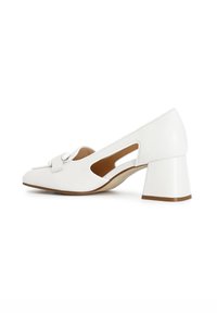 Zapato de tacón cuadrado de cuero blanco con laterales recortados, punta redondeada y lazo decorativo en la parte delantera. Textura suave y diseño minimalista.