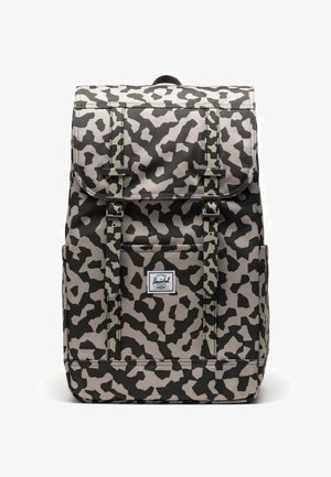 Sac à dos noir et beige à motif léopard avec deux sangles supérieures, deux boucles à l'avant et une petite poche avant ornée d'un écusson logo.
