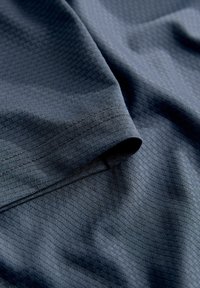 Tissu bleu foncé avec une texture à fines mailles, des plis doux et un détail de couture visible.