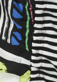 Multikleurige stof met gedurfde strepen in zwart en wit, met grafische elementen in blauw, groen, roze en geel. Textuur en geplooid ontwerp.