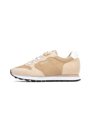 Chaussures de sport beiges avec des panneaux en daim et en tissu, des lacets blancs, une semelle rembourrée et une semelle extérieure en caoutchouc noir. Design minimaliste avec un branding clair.