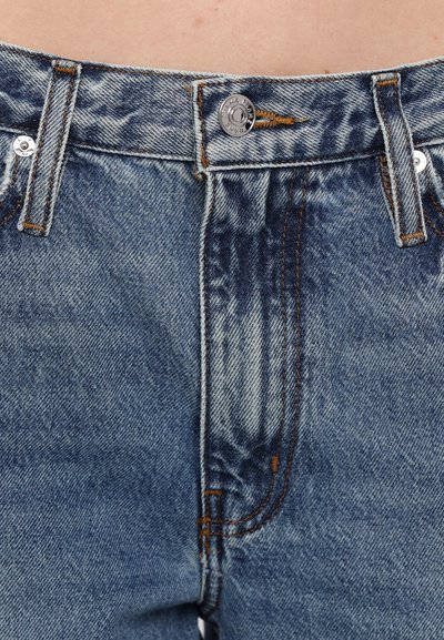 Blå denim jeans med høy midje, kobbersting og sølvknapplukking. Stoffet har et svakt falmet utseende.