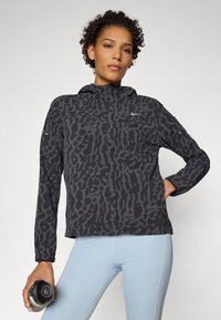 Nike hooded jacket with a black and gray animal print pattern, featuring a front zipper, elastic cuffs, and a relaxed fit.