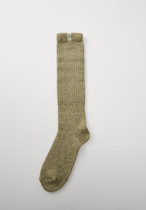 Chaussette montante olive vert avec un motif tricoté texturé ; présente un renforcement à la pointe et un revers plié avec le logo "UGG".