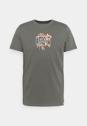Grünes Baumwoll-T-Shirt mit kurzen Ärmeln, das ein gesticktes Logo in Weiß und Orange zeigt, umrahmt von einem rechteckigen Rahmen mit botanischen Akzenten.