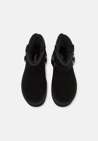 Paire de bottines en daim noir avec doublure intérieure rembourrée et détail de boucle, vue de dessus sur fond blanc.