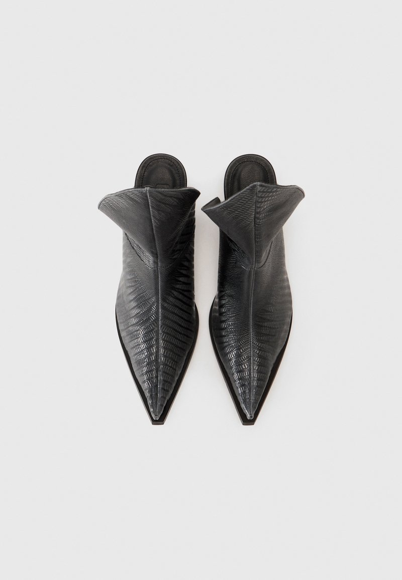 Chaussures noires à enfiler avec un bout pointu et un col haut replié. Fabriquées en cuir texturé avec un motif reptile. Semelles plates.