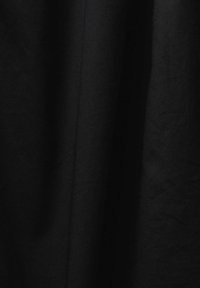 Tissu noir avec des plis verticaux subtils et une surface légèrement texturée, créant des ombres douces et des reflets.