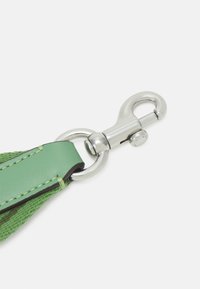 Grönt läderband med texturerad vävd detalj, utrustat med en silverfärgad metallkarbinhake och ringfäste för säker fastsättning.