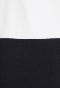 Due sezioni orizzontali di tessuto: metà superiore in bianco, metà inferiore in nero. Texture morbida con bordi puliti e senza motivi o decorazioni visibili.