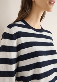 Navyblauer und weißer gestreifter Pullover aus weichem, strukturiertem Strickstoff; verfügt über einen runden Ausschnitt und kurze Ärmel.