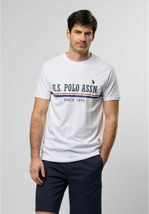 Witte katoenen t-shirt met het "U.S. POLO ASSN." logo in marineblauw, met een horizontale gestreepte accent eronder. Gecombineerd met marineblauwe shorts.