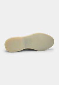 Talpă de pantof din cauciuc cu o suprafață netedă de culoare bej, având o ușoară curbă și un detaliu cu logo embosat în centru. Design curat și minimalist.