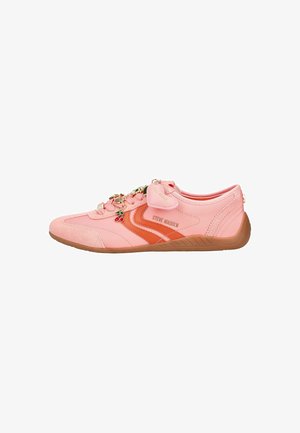Różowo-pomarańczowy niski sneaker z beżową podeszwą, ozdobnym zawieszanym wiszakiem w kształcie wiśni oraz logo „Steve Madden” po boku.