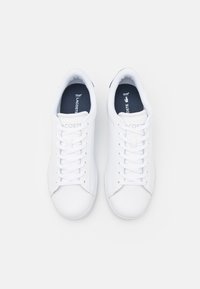 Sneaker bianche in pelle con texture liscia, lacci piatti e punta tonda. Presentano il logo sulla linguetta e una soletta scura in contrasto.