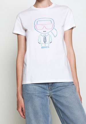 Person iført en hvid t-shirt med en simpel linjetegning af en karakter med hestehale og store pink solbriller på forsiden.