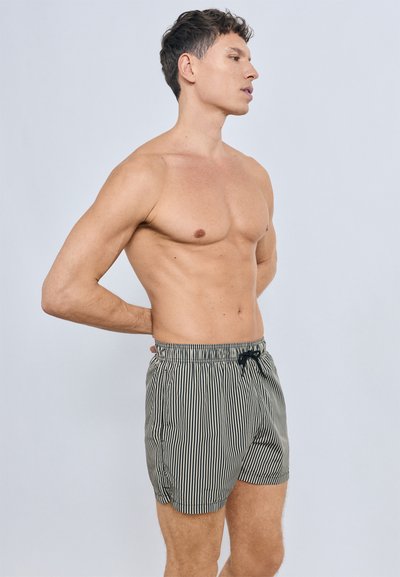 Short de bain rayé en vert foncé et blanc, avec une taille élastique et un cordon de serrage. Le tissu est léger avec une texture lisse.