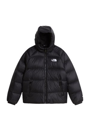 Noor inimene, kes kannab musta peapaela, musta kapuutsiga sulejopet ja musta pükse, kõigil The North Face'i logo, käed jope taskutes.