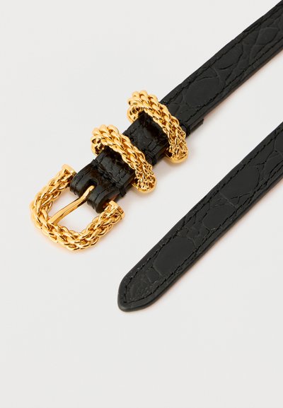 Fekete texturált bőröv fonott arany csattal és két arany láncos övhurkokkal, fehér háttéren.