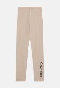 Béžové legíny vyrobené z mäkkého materiálu s priliehavým strihom. Na dolnej časti ľavej nohavice je čierne logo "Calvin Klein".