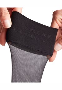 Svarta nylonstrumpbyxor med en mönstrad linning med präglat varumärkesnamn "FALKE." Benpartiet är genomskinligt och subtilt mönstrat.