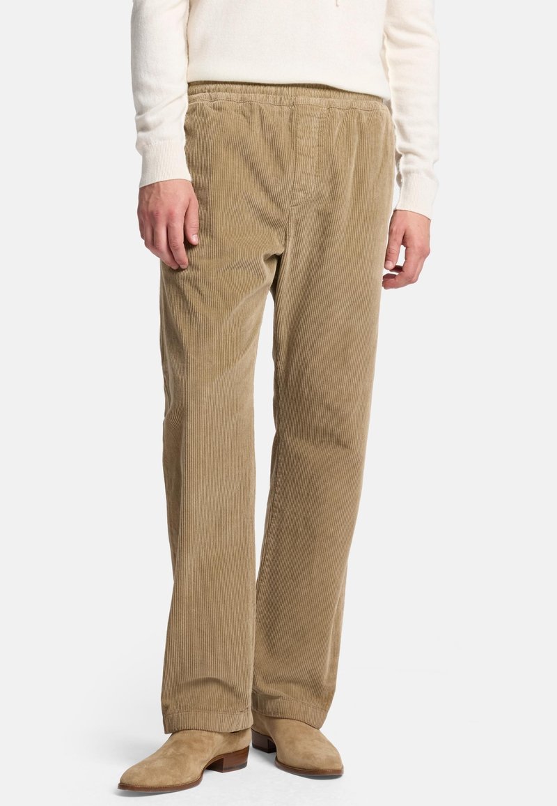 Beige Corduroyhose mit einem weiten Bein Design, elastischem Bund und vertikaler Rippstruktur; kombiniert mit beige Wildleder-Ankle Boots.
