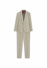 Costume slim beige en deux pièces avec blazer à un bouton et pantalon droit, avec une étiquette intérieure rouge portant le nom de la marque.