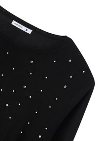 Maglione nero con scollatura rotonda, decorato con dettagli bianchi e argentati sparsi. Realizzato in un tessuto morbido con una texture liscia.