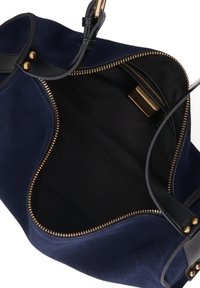 Marineblauwe suède handtas met een zwarte stoffen voering. Gouden rits en hardware-accenten. Zachte textuur met een gestructureerd, gebogen ontwerp.