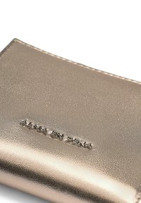 Metallic gold wallet with a textured surface, featuring embossed "ALMA EN PENA" logo, and an elegant, slim design.