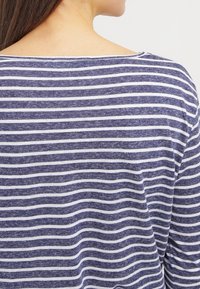 Marineblau-weiß gestreifter Oberteil mit lockerer Passform, weichem Material und weitem Ausschnitt, der abwechselnd dicke und dünne Streifen zeigt.