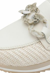 Zapatilla blanca de cuero con detalles de yute tejido; presenta un adorno de cadena marmoleada en blanco y marrón y una suela de goma beige.
