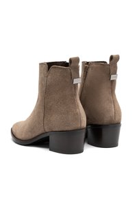 Stivali ankle in suede marrone con punta arrotondata, chiusura con zip e linguette. Presentano un tacco basso e robusto e una suola liscia nera.